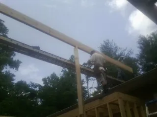 Carpenter setting a ridge beam over a new addition frame — Ice Dam Removal by Roofing Brothers in Hope Mills