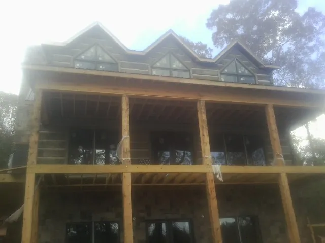 Dormers and porch framing on a large log home under construction — Roof Coating work by our crew in Hope Mills