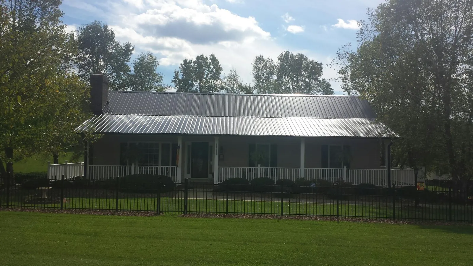 Gray metal roof on a brick ranch with a full width front porch — Gutter Guard Installation work by our crew in Hope Mills