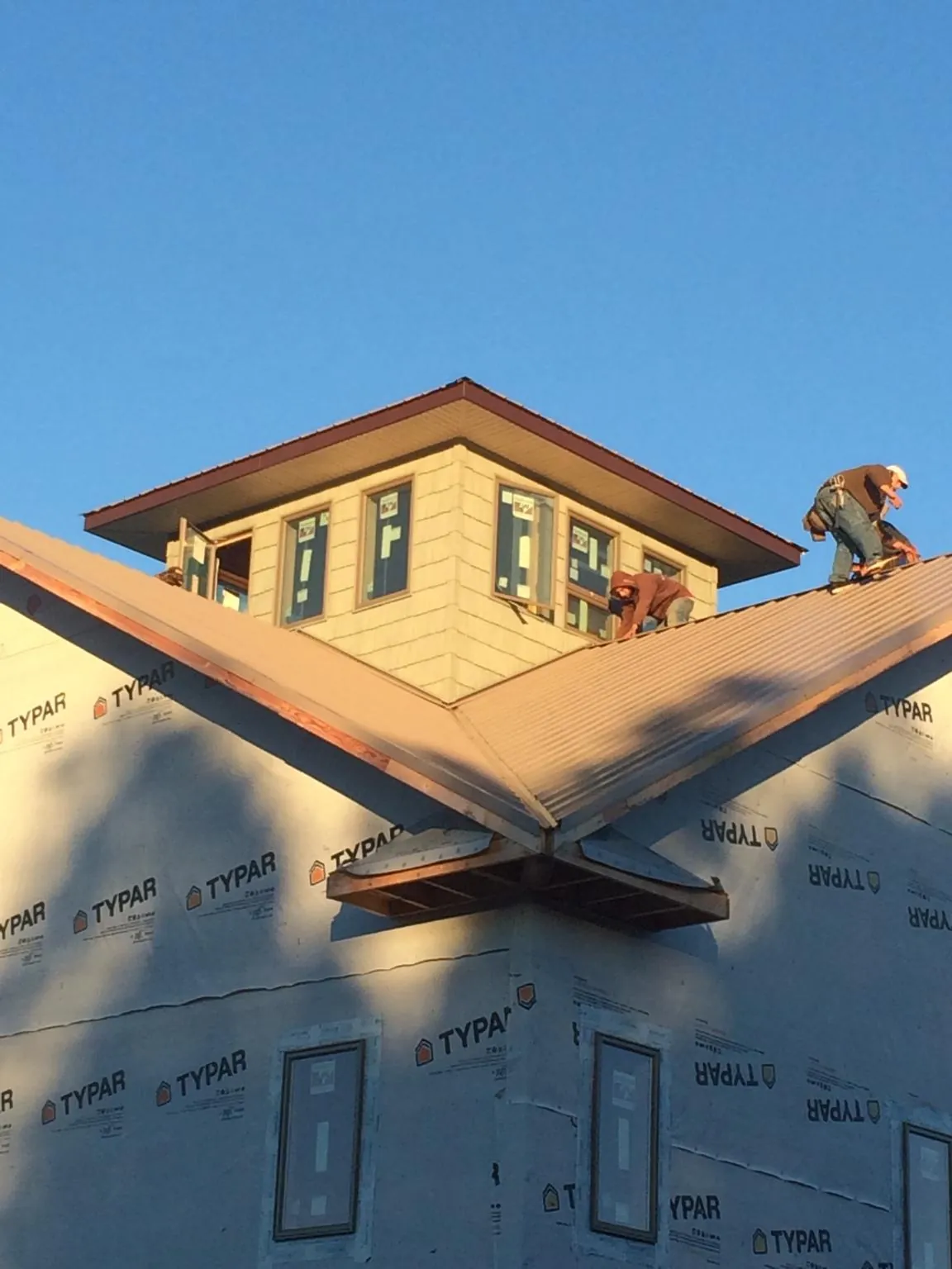 Roofers working around a rooftop cupola on a new metal roof at sunset — Roof Waterproofing in Hope Mills by Roofing Brothers
